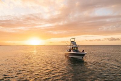 Long fishing boat at sea and colors at sunset wall mural