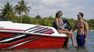 Man Looking at Woman Sitting on Deck of Bayliner Boat with Mercury Engine