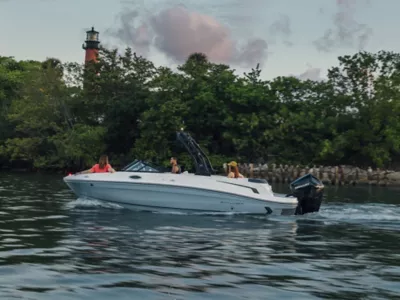 Man Driving Bayliner Deck Boat, Women Riding at Bow and Stern, Starboard View, Boat Underway