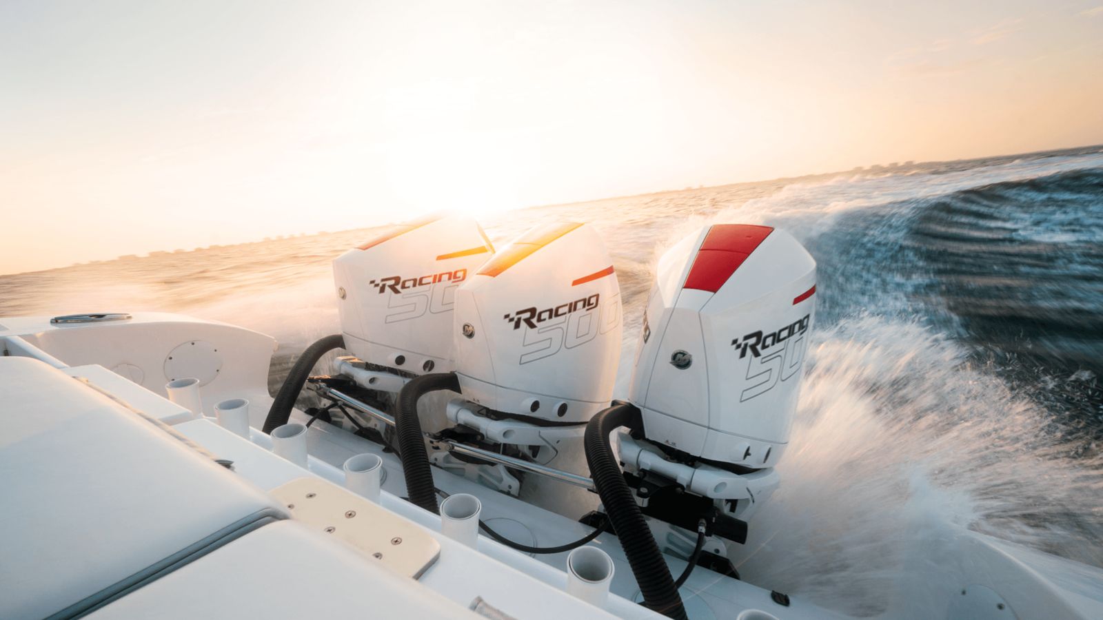 Three white Mercury Racing 500R outboards powering a performance boat at golden hour