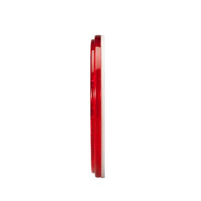 Red round stick-on reflector, side view, showcasing slim profile and adhesive backing for easy attachment.