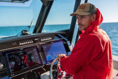 Captain at Helm of Boston Whaler Boat Wearing Rain Gear