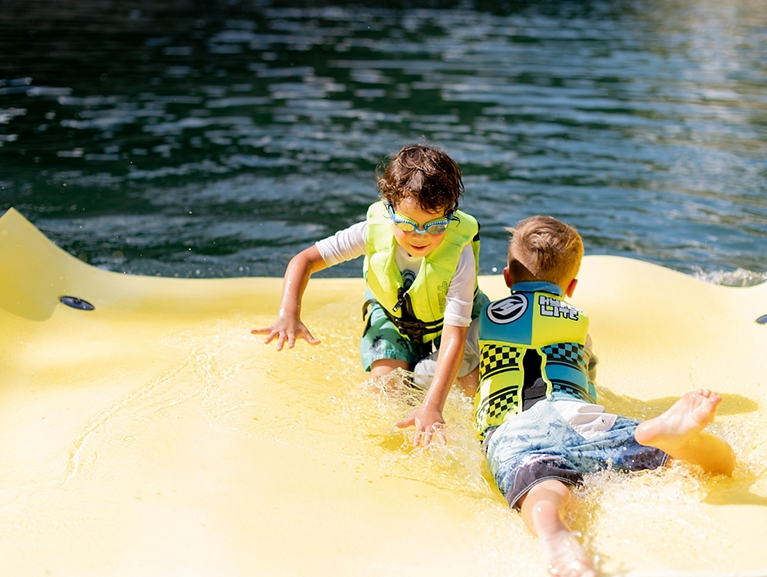 Children Swimming On Raft In Water