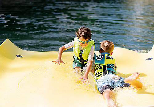 Children Swimming On Raft In Water