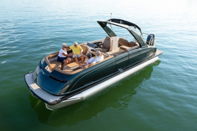 Harris Crowne 250 pontoon boat on a body of water with four people sitting and standing on it.