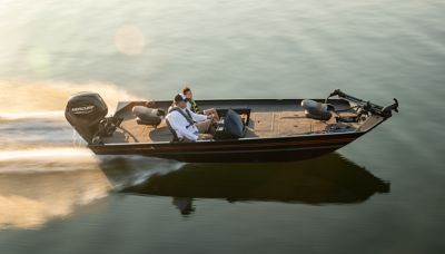 Side profile of a 2022 Lowe Legacy boat gliding across calm water. The boat is black with red accents and powered by a Mercury outboard motor. Two people are seated onboard—one at the helm and the other beside them. The smooth water reflects the sunlight, enhancing the sleek design of the boat.
