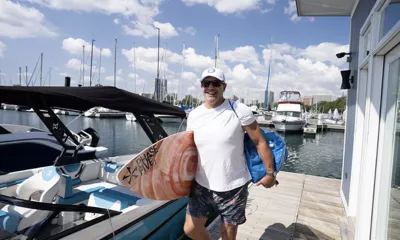 man holding surfboard walking on the dock