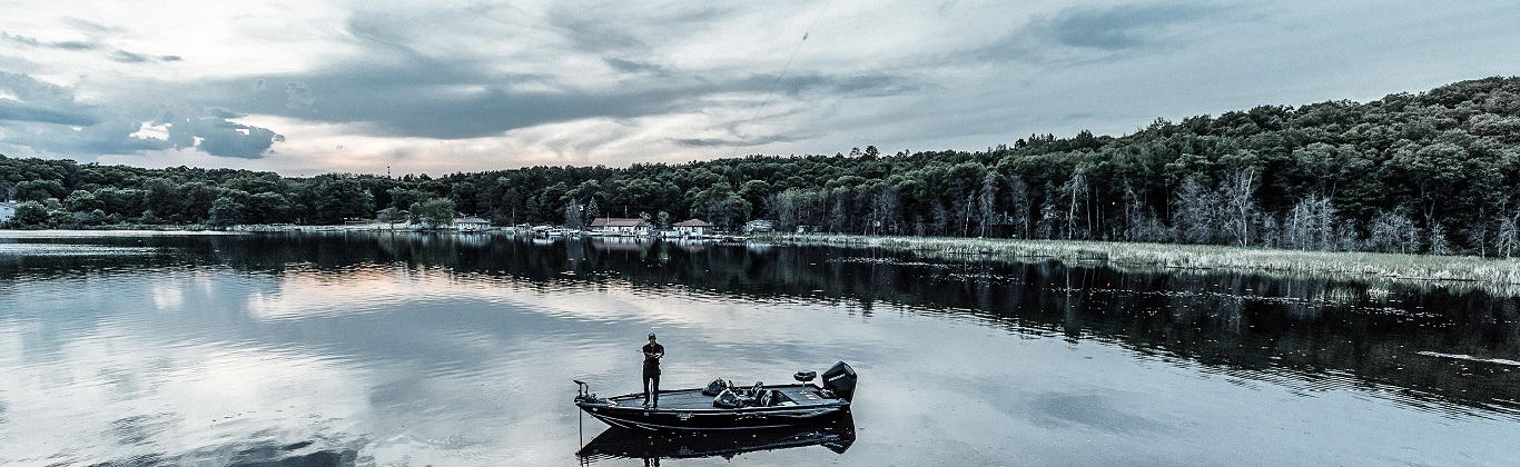 Fisherman standing on boat in scenic lake