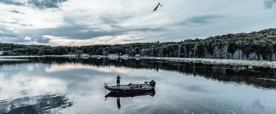 Fisherman standing on boat in scenic lake