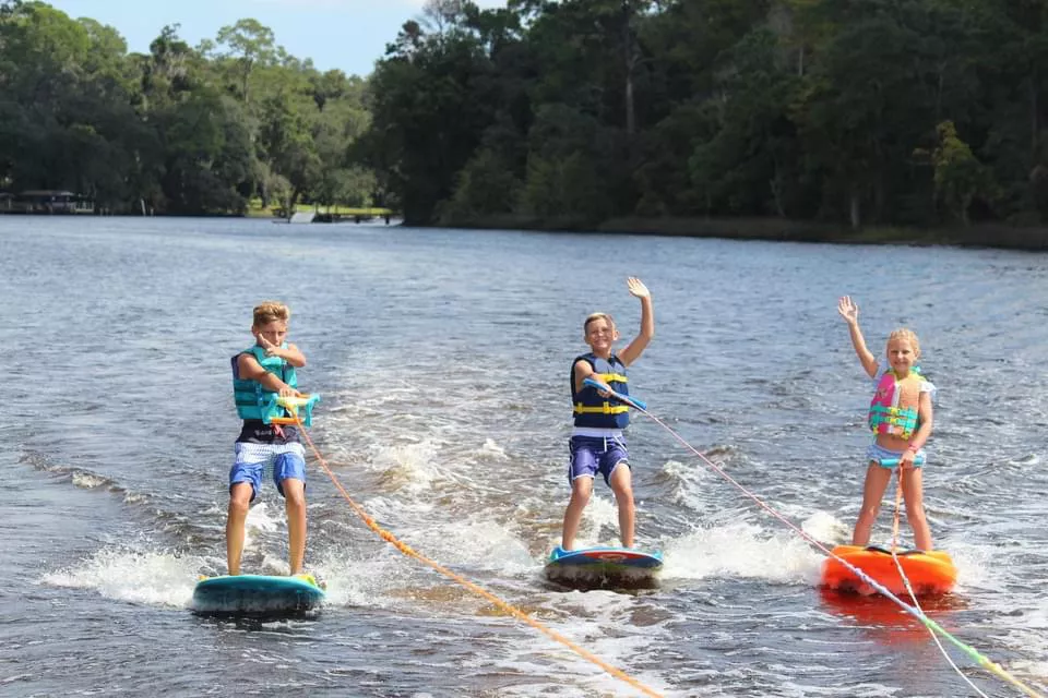 kids waving while waterskiing