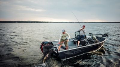 Fisherman standing on boat in scenic lake