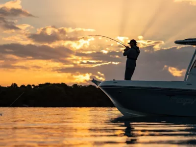 Man Standing on Bow at Bayliner Trophy Center Console Fishing Boat Reeling in Fish