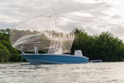 Fisherman throwing net from Whaler boat