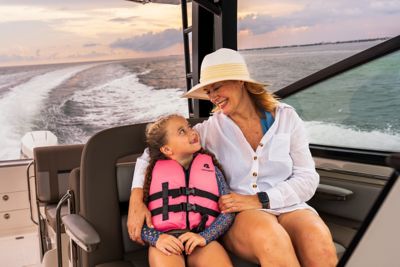 Adult and child wearing life jacket riding on Boston Whaler boat, underway