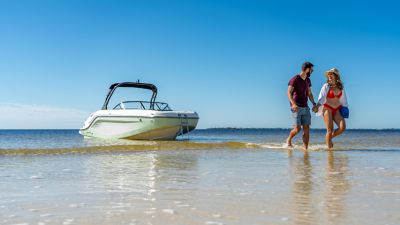 Man and Woman Walking Ashore from Anchored Bayliner Bowrider Boat