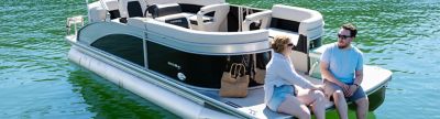 Couple enjoying a picnic on a Harris Pontoon Boat Breeze 210 CW anchored on a calm lake.