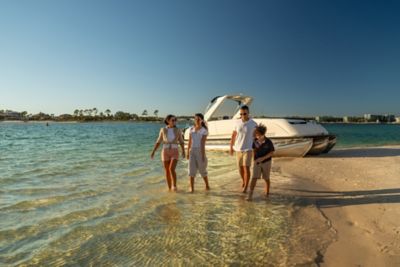Family walking through the water in front of a 2024 Harris Crowne 250 Pontoon Boat