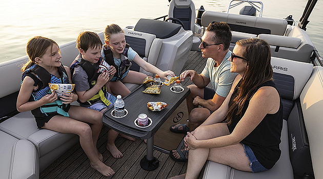 Family eating snacks on the bow table on a Harris Solstice pontoon