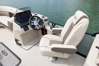  Helm of the Sunliner pontoon boat showing the steering wheel, audio control, phone charger, cupholder, and other control switches. 