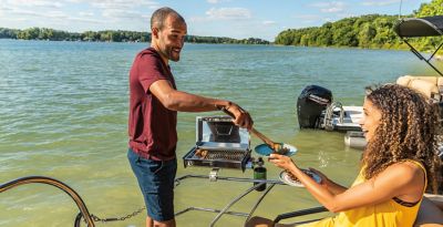 Couple grilling on a Harris Solstice 230 SL