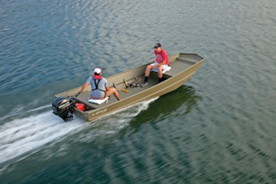 Two people are riding in a Lowe 2020 Jon L 1648 M Aura boat on a body of water. The boat is moving at a moderate speed, creating a wake behind it. One person is seated at the rear operating the motor, while the other person is seated towards the front. The boat has an olive-green color and appears to be made of aluminum. The water around them is calm with gentle ripples.
