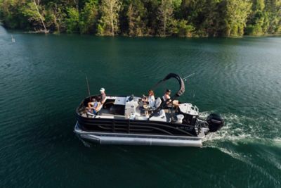 Lowe Sf 194 pontoon boat riding across the water with a family aboard fishing. In the background there is large green trees.