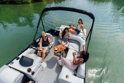 Group of ladies sitting on a Lowe pontoon boat with drinks and snacks.