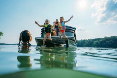 Three girls in life vests jumping off a Lowe pontoon boat.
