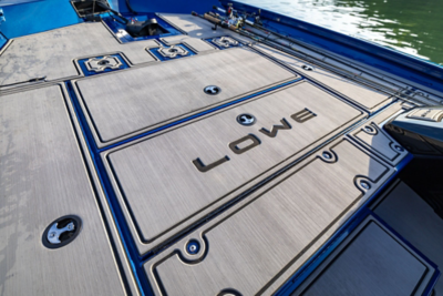 View of a blue-and-gray Lowe Stinger 175 bow deck with LOWE imprinted into the EVA flooring and fishing rods secured on the side in rod holders. 
