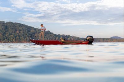 An angler casting a rod from the bow deck of a red Lowe Stinger 195 crappie and bass boat powered by a Mercury Pro XS outboard engine on an open lake.