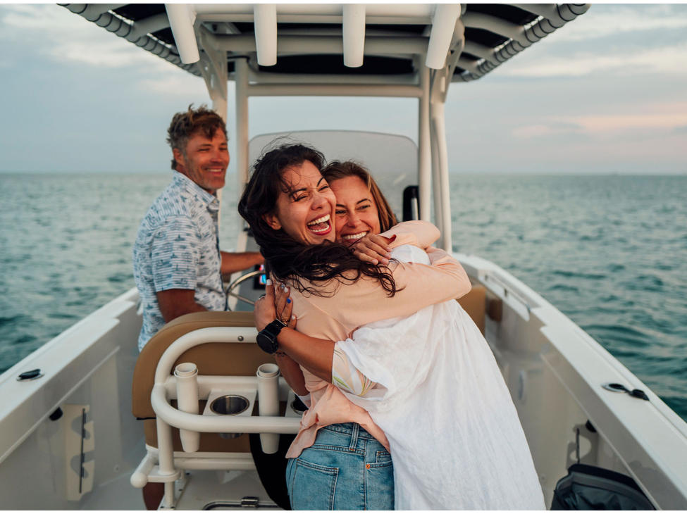Two women hugging tightly on a boat, enjoying the peacefulness of the ocean.