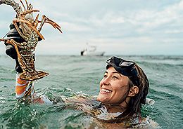 A woman holding a lobster in the ocean