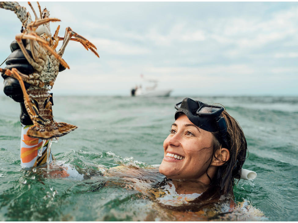 A woman holding a lobster in the ocean